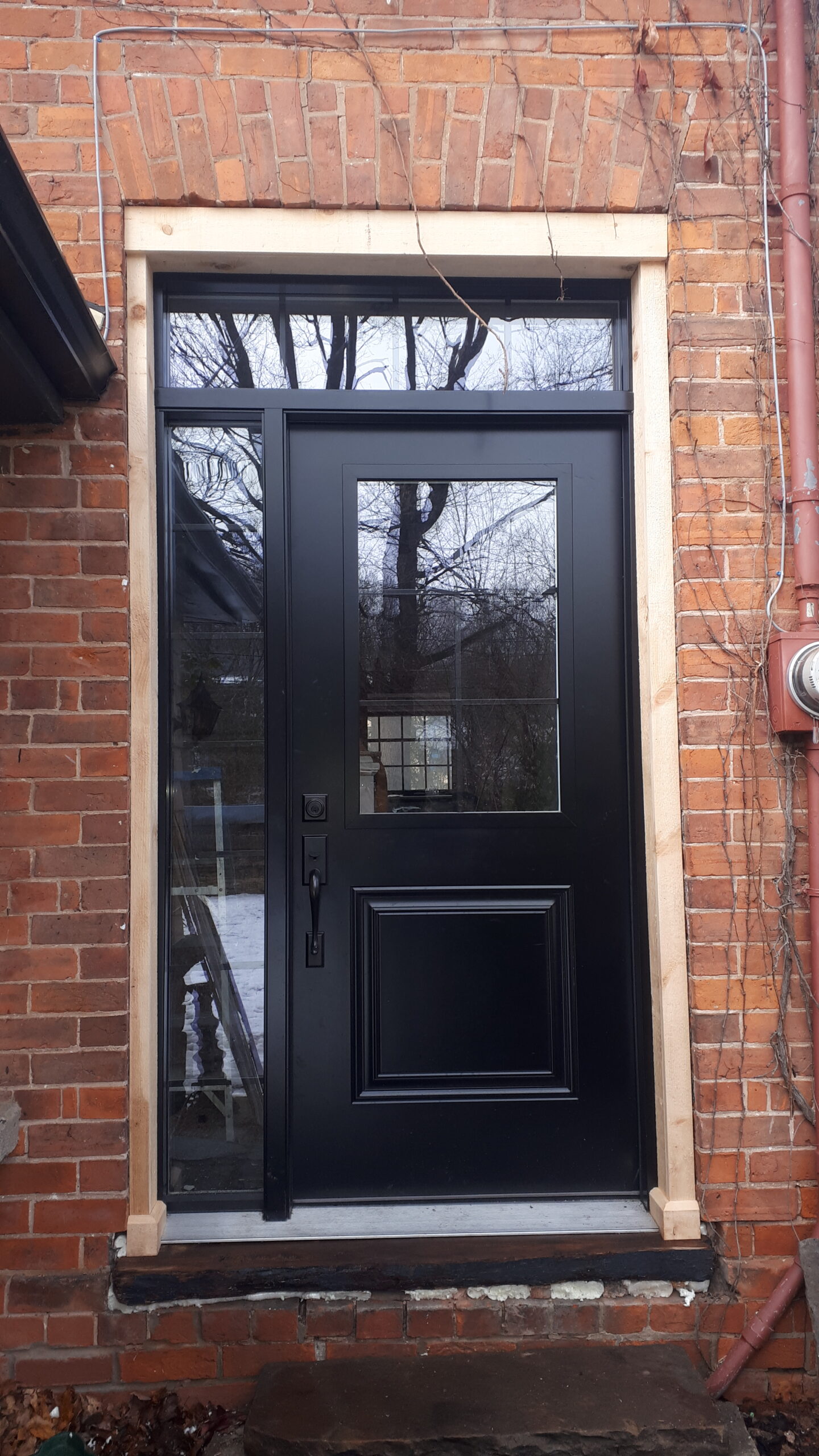 Installing a new black front entry door with transom window above